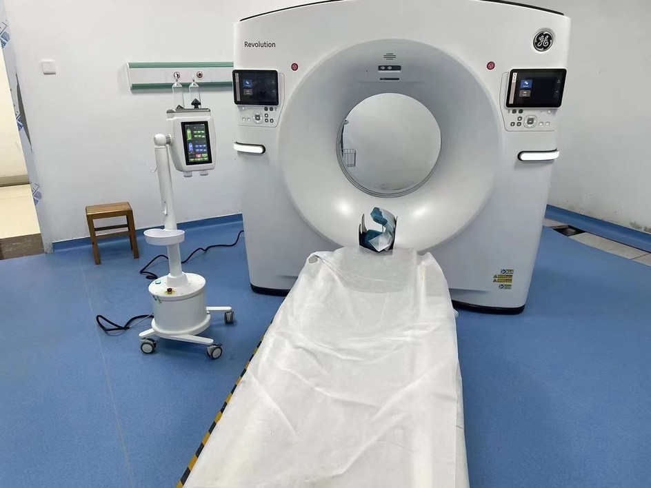 CT scanner room with a contrast injector on a floor pedestal beside the table